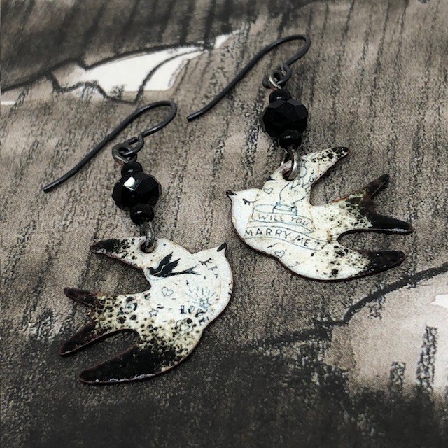 Petites boucles d'oreilles asymétriques et poétiques composées de pendentifs en cuivre émaillé, en forme d'hirondelle. Bijoux uniques de créateur.