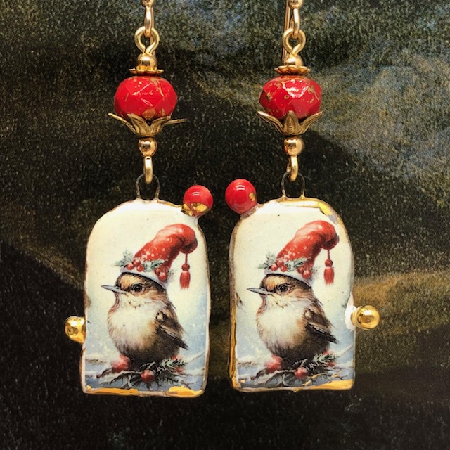 Boucles d’oreilles bohèmes composées de pendentifs en céramique représentant un oiseau avec un bonnet rouge décoré d'une guirlande de houx. Bijoux uniques.