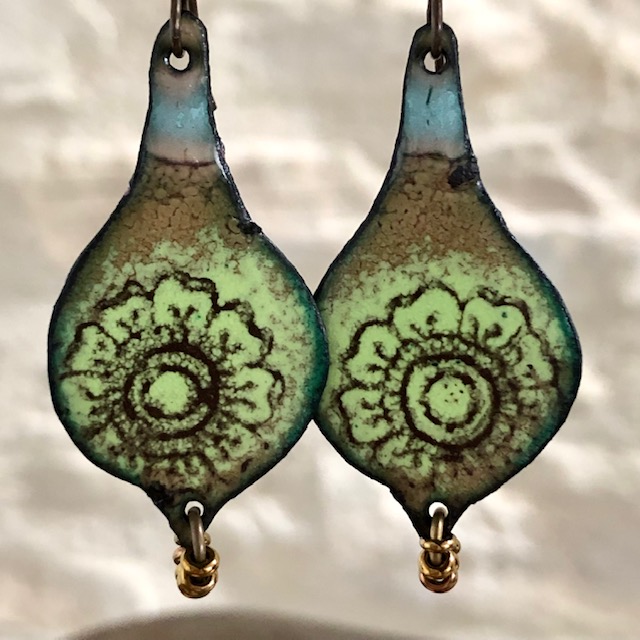 Boucles d'oreilles bohèmes composées de pendentifs en cuivre émaillé avec un motif de mandala noir sur un fond couleur jade. Pièces uniques.