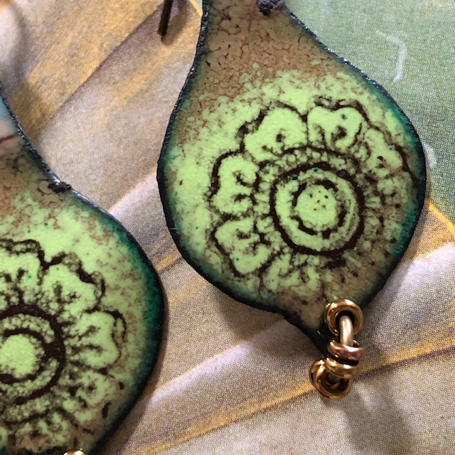 Boucles d'oreilles bohèmes composées de pendentifs en cuivre émaillé avec un motif de mandala noir sur un fond couleur jade. Pièces uniques.
