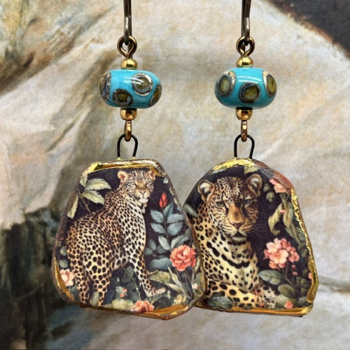 Boucles d’oreilles asymétriques composées de pendentifs en céramique avec un motif léopard et de perles en verre bleu turquoise et bronze. Bijoux uniques.