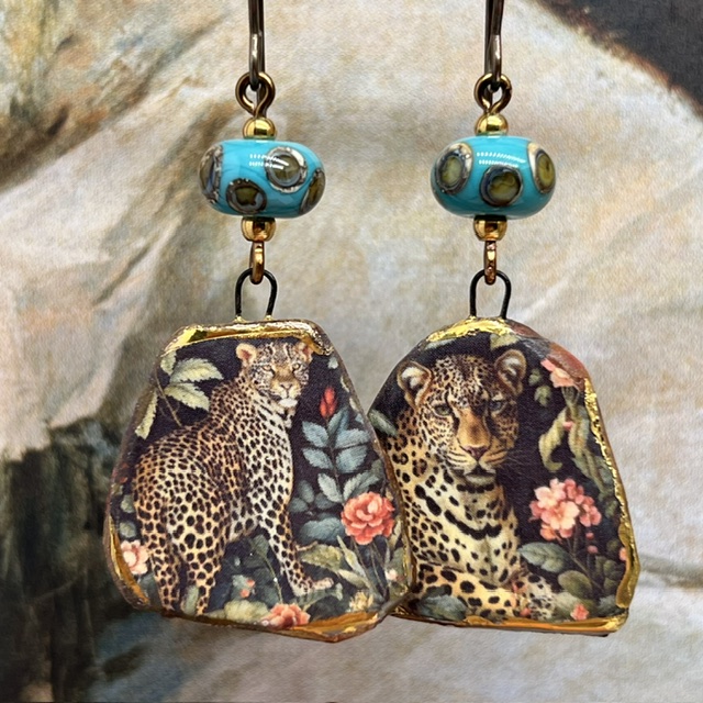 Boucles d’oreilles asymétriques composées de pendentifs en céramique avec un motif léopard et de perles en verre bleu turquoise et bronze. Bijoux uniques.