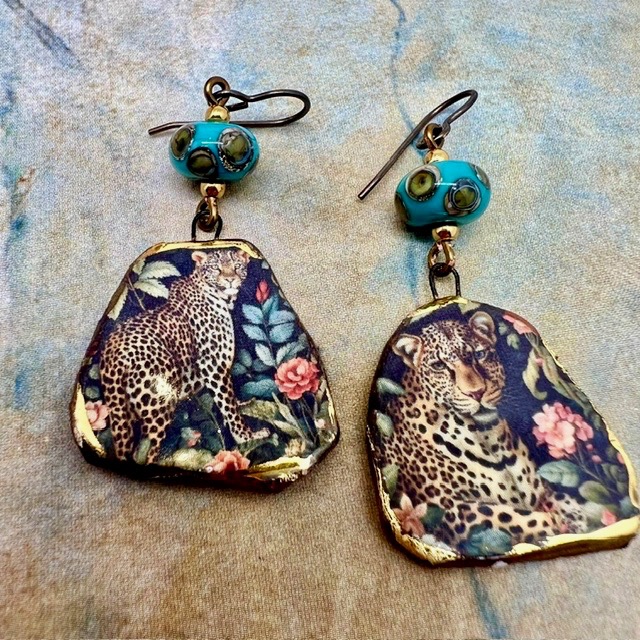 Boucles d’oreilles asymétriques composées de pendentifs en céramique avec un motif léopard et de perles en verre bleu turquoise et bronze. Bijoux uniques.