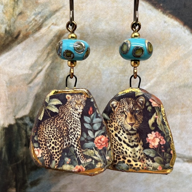 Boucles d’oreilles asymétriques composées de pendentifs en céramique avec un motif léopard et de perles en verre bleu turquoise et bronze. Bijoux uniques.