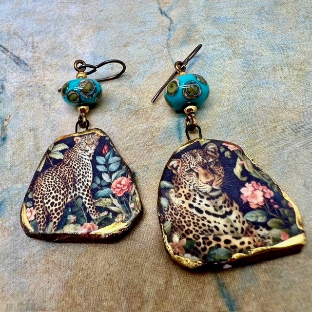 Boucles d’oreilles asymétriques composées de pendentifs en céramique avec un motif léopard et de perles en verre bleu turquoise et bronze. Bijoux uniques.