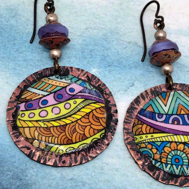 Boucles d'oreilles vintage composées de pendentifs artisanaux ronds multicolore en cuivre émaillé, de perles en verre tchèque lilas.