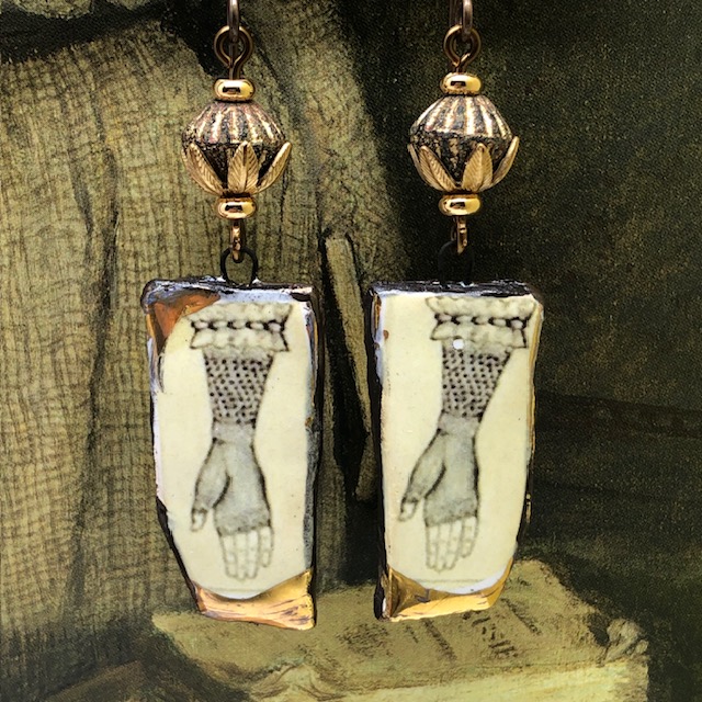 Boucles d’oreilles asymétriques composées de pendentifs en céramique représentant une main avec une mitaine en dentelle couleur sépia. Bijoux uniques.
