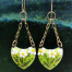 Boucles d'oreilles asymétriques et bohèmes composées de pendentifs en cuivre émaillé représentant des marguerites blanches sur un fond vert. Bijoux uniques.