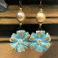 Boucles d'oreilles asymétriques composées de pendentifs en céramique avec une forme de marguerite bleu turquoise et or. bijoux uniques de créateur.