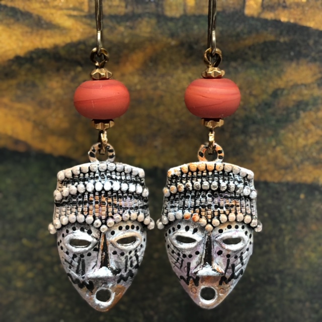 Boucles d'oreilles style ethnique composées de pendentifs artisanaux en cuivre émaillé en forme de masque africain. Pièces uniques.
