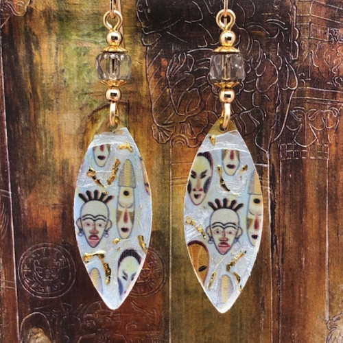 Boucles d'oreilles bohèmes chic composées de pendentifs en laiton émaillé représentant des masques africains sur un fond blanc cassé et or. Bijoux uniques.