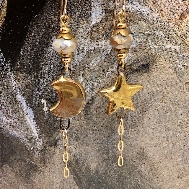Longues boucles d'oreilles asymétriques Moon and Star composées de pendentifs en céramique dorée. Bijoux uniques de créateur.