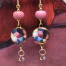 Longues boucles d’oreilles asymétriques composées de pendentifs ronds en céramique avec un motif de mosaïque rose et violet. Bijoux uniques.