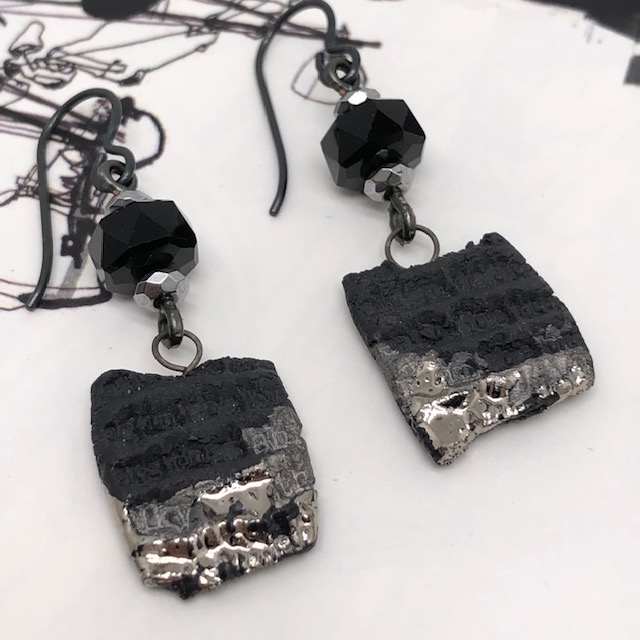 Boucles d'oreilles graphiques noires et argent, de forme carré, composées de pendentifs artisanaux en porcelaine et de perles en cristal Swarovski noires.