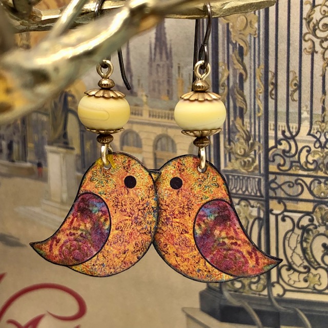 Boucles d'oreilles bohème composées de pendentifs en cuivre émaillé représentant des oiseaux cardinal, orange et rouge. Pièces uniques.
