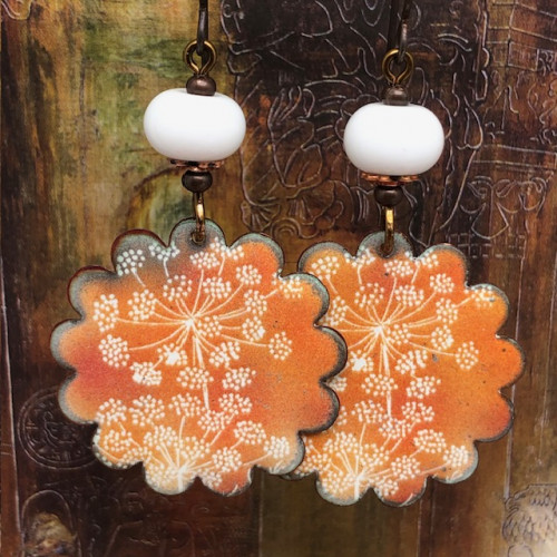 Grandes boucles d’oreilles bohèmes composées de pendentifs en cuivre émaillé avec des fleurs de carotte sur un fond orangé. Bijoux uniques de créateur.