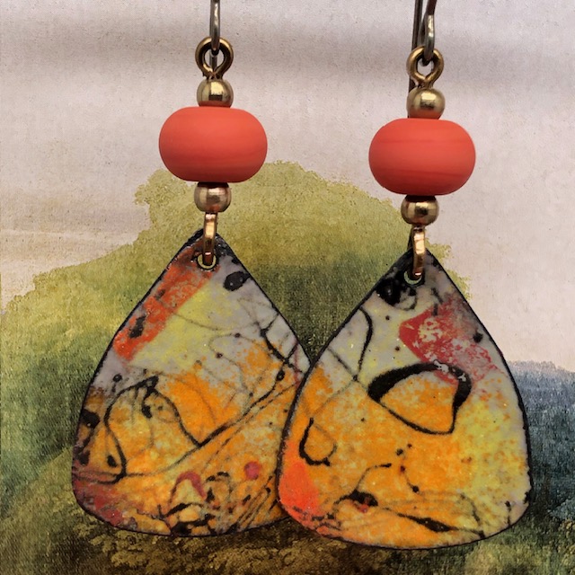 Boucles d'oreilles asymétriques composées de pendentifs en cuivre émaillé avec un motif abstrait noir, orange et jaune. Bijoux uniques.