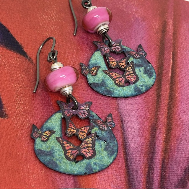 Boucles d'oreilles bohème chic composées de pendentifs en cuivre émaillé représentant des papillons roses et rouges. Modèle unique.