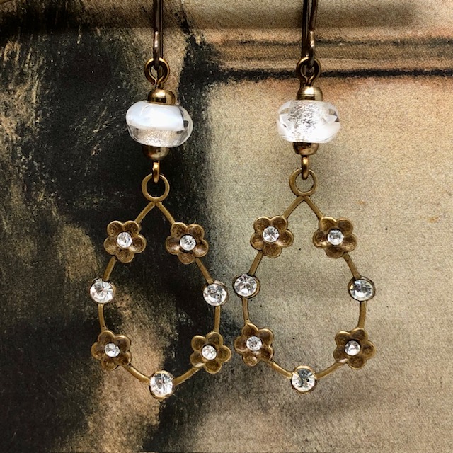Boucles d'oreilles vintage composées de pendentifs en laiton doré ornées de petites fleurs serties de cristaux blancs. Bijoux uniques de créateur.