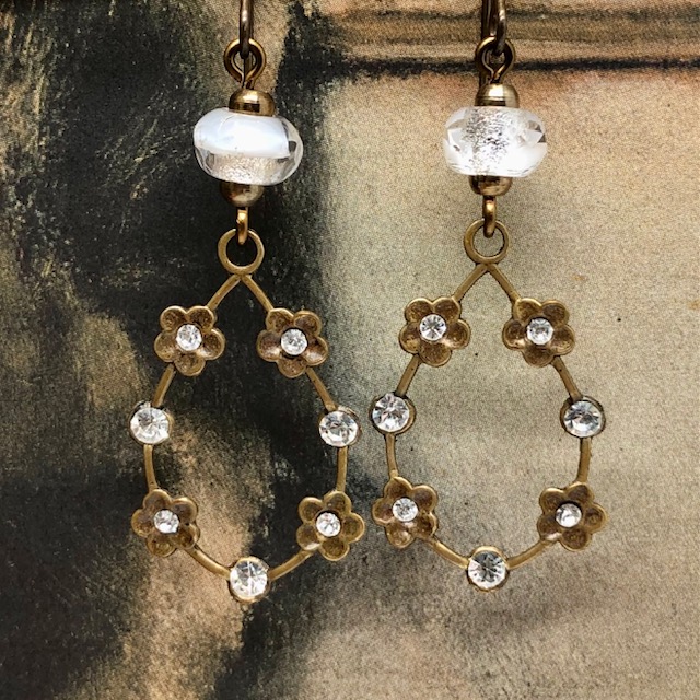 Boucles d'oreilles vintage composées de pendentifs en laiton doré ornées de petites fleurs serties de cristaux blancs. Bijoux uniques de créateur.