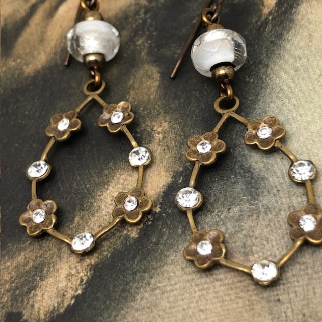 Boucles d'oreilles vintage composées de pendentifs en laiton doré ornées de petites fleurs serties de cristaux blancs. Bijoux uniques de créateur.