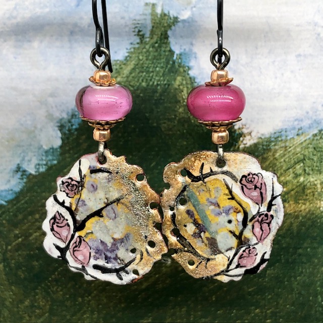 Boucles d’oreilles bohèmes asymétriques composées de pendentifs en cuivre émaillé avec un motif de rose sur un fond or. Bijoux uniques de créateur.