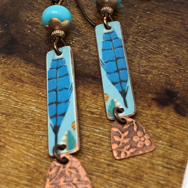 Boucles d'oreilles bohème plumes bleues composées de pendentifs artisanaux en cuivre illustré et de perles lampwork. Pièces uniques.