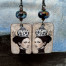 Boucles d'oreilles uniques composées de pendentifs en cuivre émaillé avec le portrait d'une femme portant une tasse en guise de chapeau.