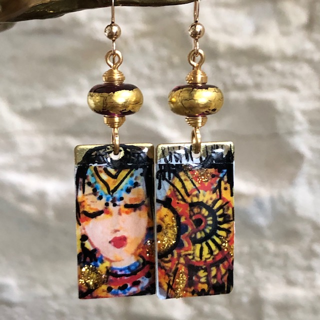 Boucles d'oreilles asymétriques composées de pendentifs en laiton émaillé, avec le visage d'une princesse hindoue et un mandala. Bijoux uniques.