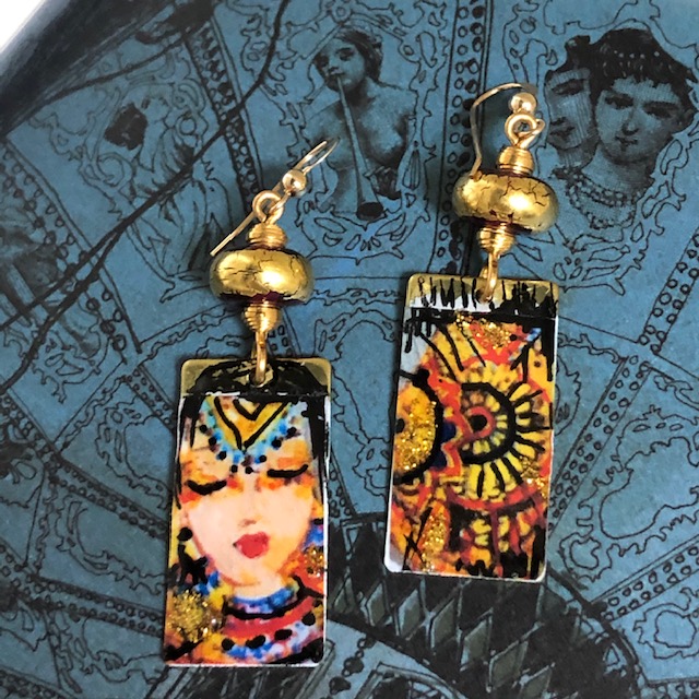 Boucles d'oreilles asymétriques composées de pendentifs en laiton émaillé, avec le visage d'une princesse hindoue et un mandala. Bijoux uniques.