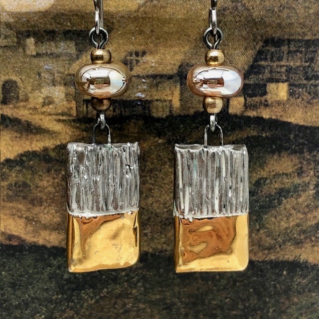 Boucles d'oreilles asymétriques et glamour composées de perles et de pendentifs en céramique or et platinum. Bijoux uniques de créateur.