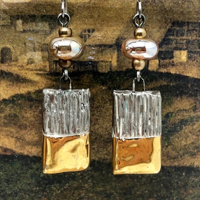 Boucles d'oreilles asymétriques et glamour composées de perles et de pendentifs en céramique or et platinum. Bijoux uniques de créateur.