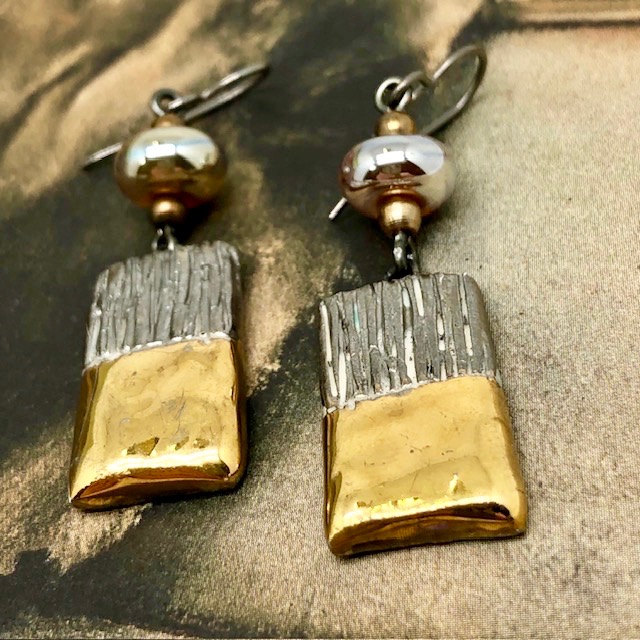Boucles d'oreilles asymétriques et glamour composées de perles et de pendentifs en céramique or et platinum. Bijoux uniques de créateur.