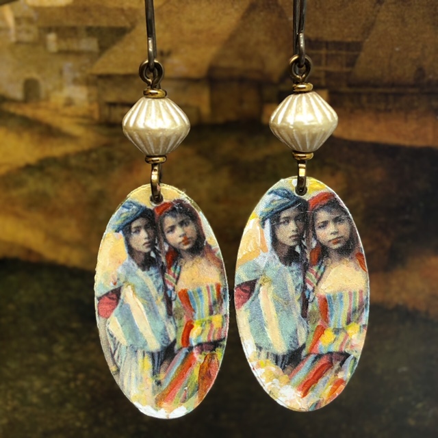 Boucles d'oreilles style ethnique composées de pendentifs en laiton illustré représentant deux jeunes filles serrées l'une contre l'autre. Pièces uniques.