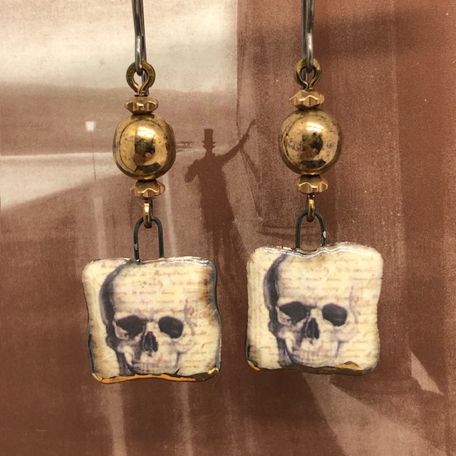 Boucles d'oreilles Calaveras composées de pendentifs carrés en céramique marron et beige représentant une tête de mort. Bijoux uniques.