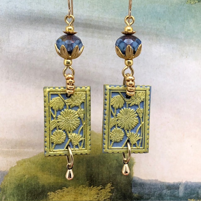 Boucles d’oreilles bohèmes composées de pendentifs en argile polymère avec un motif floral vert sur un fond bleu. Bijoux uniques et poétiques.
