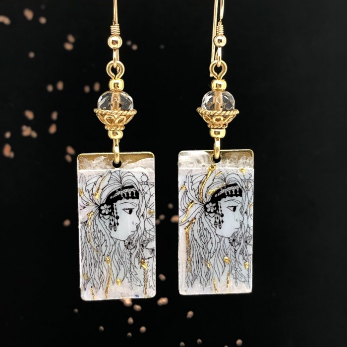 Boucles d'oreilles bohème chic composées de pendentifs en laiton émaillé argent et or, représentant un visage de femme. Pièces uniques.