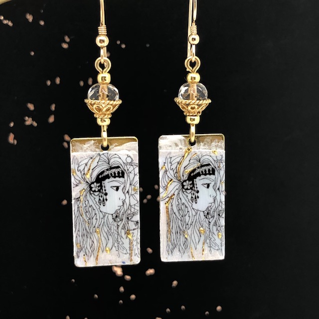 Boucles d'oreilles bohème chic composées de pendentifs en laiton émaillé argent et or, représentant un visage de femme. Pièces uniques.