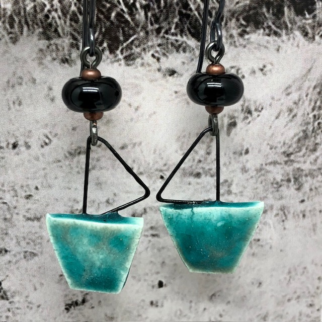 Boucles d'oreilles de créateur composées de pendentifs en céramique turquoise et noir, avec une forme de voilier. Bijoux uniques.