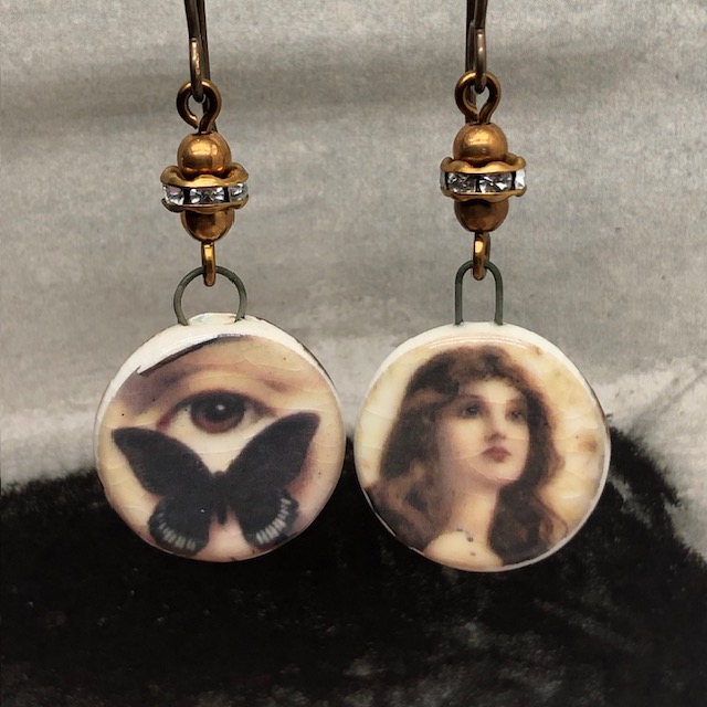 Boucles d'oreilles asymétriques composées de pendentifs sépia en céramique avec un papillon, un oeil et le portrait d'une femme. Bijoux uniques de créateur.