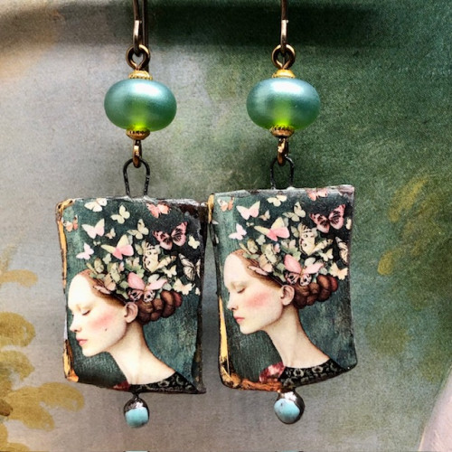 Boucles d’oreilles bohèmes asymétriques composées de pendentifs en céramique avec le portrait d'une femme entourée de papillons. Bijoux uniques.