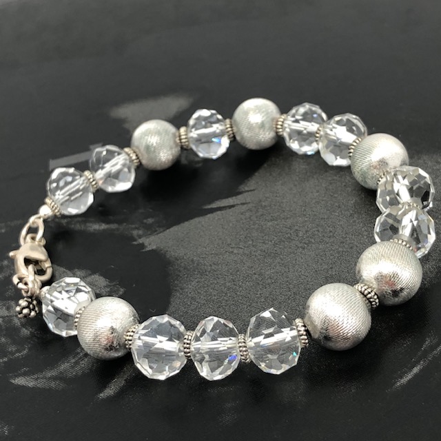 Ce bracelet lumineux est composé de jolies perles facettées en cristal et de perles en métal argenté. Fermoir et breloques en argent.
