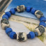 Bracelet élastique gris bleu, composé de perles artisanales cylindriques, de perles indiennes bleu Klein et de perles de rocailles tchèques. Modèle unique.