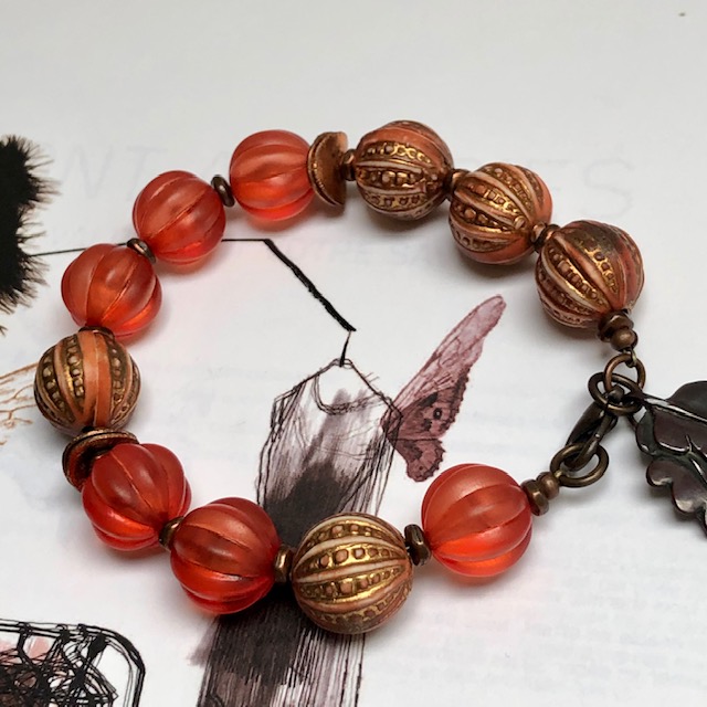 Bracelet composé de jolies perles en acrylique rose cuivré, orange brûlée et de différentes perles en cuivre. Pièce unique.