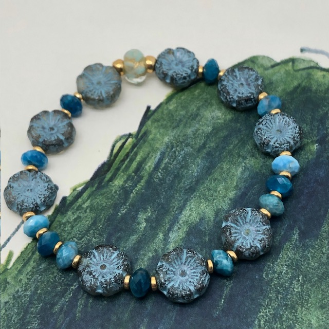 Bracelet élastique asymétrique, composé de perles en apatite et de perles en verre de Bohême bleu ciel en forme de fleur. Bracelet stretch de créateur.