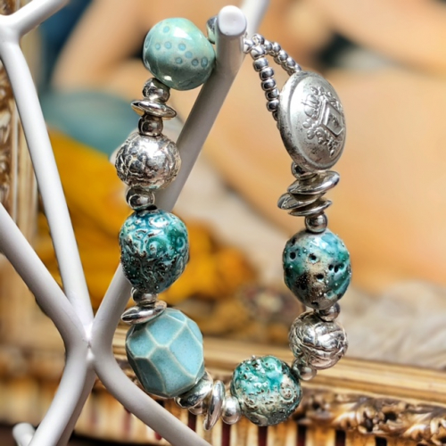 Bracelet composé de perles artisanales en céramique bleu-vert et argentées et de perles de rocaille. Pièce unique.