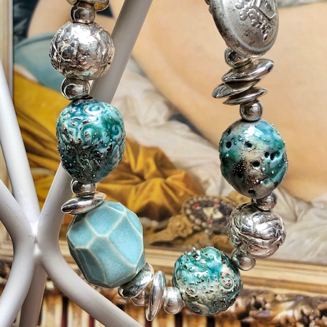 Bracelet composé de perles artisanales en céramique bleu-vert et argentées et de perles de rocaille. Pièce unique.