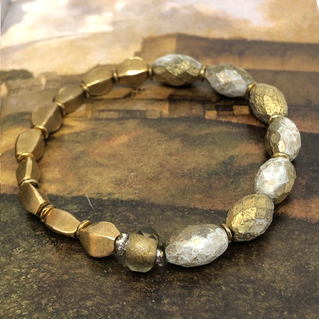 Bracelet élastique bohème chic composé de perles en verre de Bohême ovales, doré et blanche et de perles africaines en laiton doré.