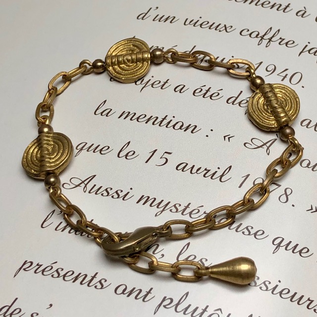 Bracelet composé de superbes perles africaines, d'une chaîne artisanale en laiton et d'une jolie breloque. Bracelet réglable.