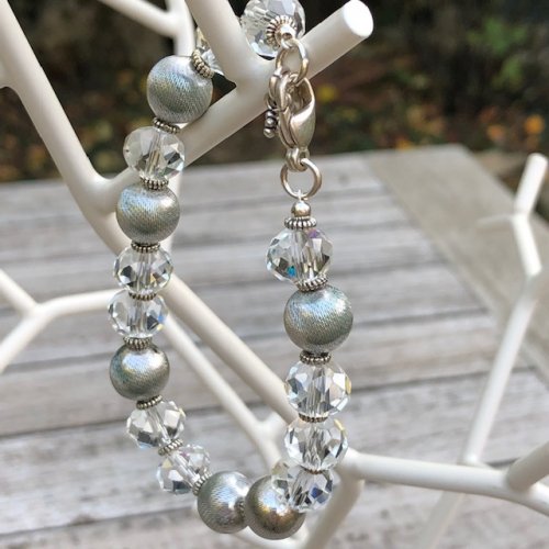 Bracelet composé de perles facettées en cristal et de perles en métal argenté. Fermoir et breloques en argent.